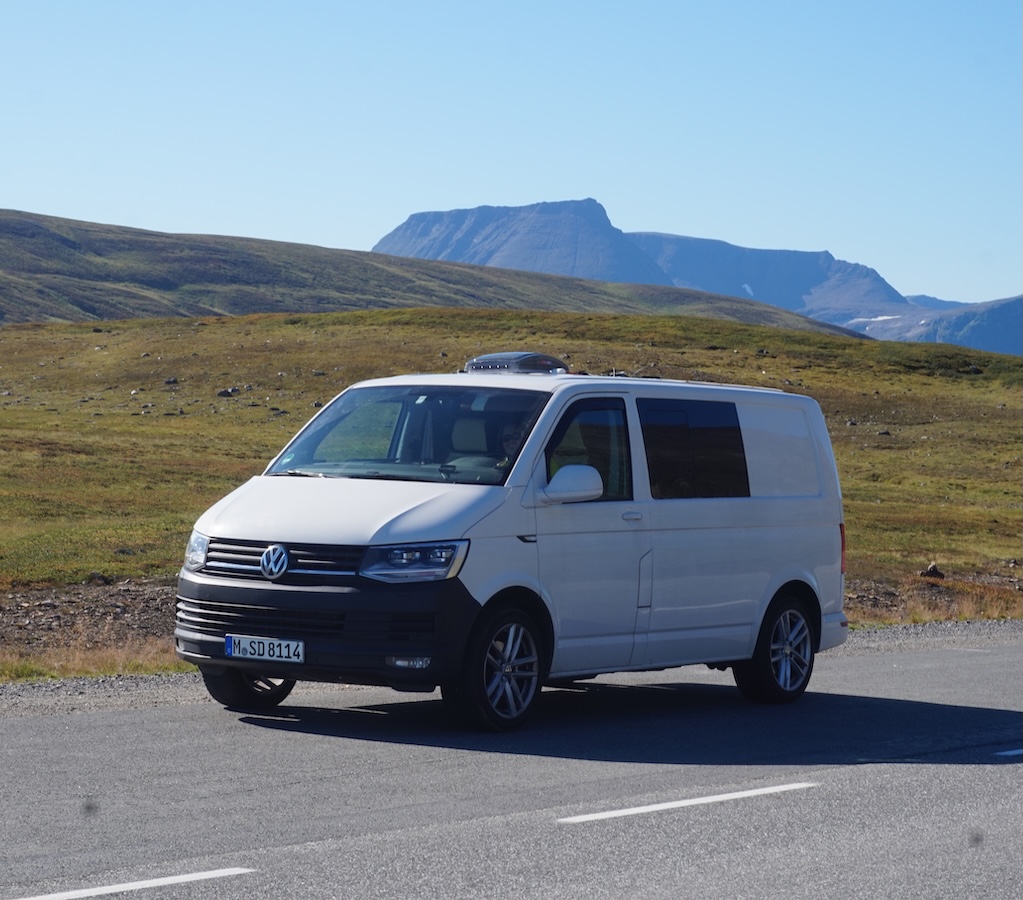 weißer Clever Camper VW Bus auf einer Straße vor weitläufiger Landschaft